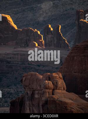 Superbes formations de grès dans le parc national des Arches, États-Unis, illuminées par le soleil couchant. Ce paysage captivant met en valeur la nature complexe Banque D'Images