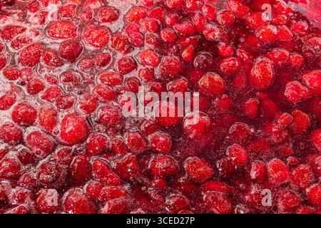 Une image en gros plan de la vibrante confiture de fraises maison, mettant en valeur la texture riche et la couleur des fraises fraîches et du sucre, parfait pour le petit déjeuner spre Banque D'Images