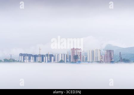 Des conditions brumeuses couvrent un quartier résidentiel adjacent à la rivière Ienisei à Krasnoïarsk. Les nouveaux bâtiments s'élèvent en évidence, leurs contours partisanes Banque D'Images