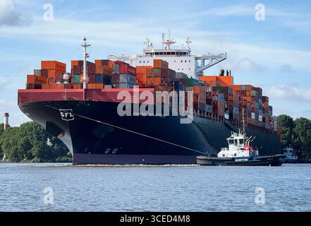 Hambourg, Allemagne. 17 août 2025. Accompagné de deux remorqueurs portuaires, le porte-conteneurs 'Vancouver Express' tourne dans l'Elbe avant d'entrer dans le port à conteneurs de Waltershof avec les terminaux d'Eurogate et le terminal à conteneurs Burchardkai (CTB) de Hamburger Hafen und Logistik AG (HHLA). Crédit : Christian Charisius/dpa/Alamy Live News Banque D'Images