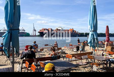 Hambourg, Allemagne. 17 août 2025. Accompagné de deux remorqueurs portuaires, le porte-conteneurs 'Vancouver Express' tourne dans l'Elbe avant d'entrer dans le port à conteneurs de Waltershof avec les terminaux d'Eurogate et le terminal à conteneurs Burchardkai (CTB) de Hamburger Hafen und Logistik AG (HHLA). Crédit : Christian Charisius/dpa/Alamy Live News Banque D'Images