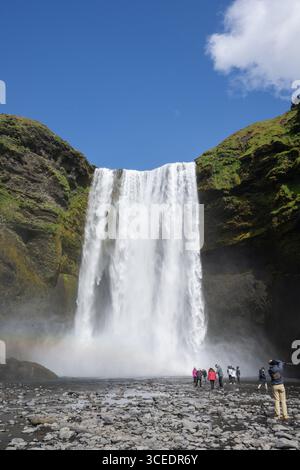 Islande, sud de l'Islande, Vik. Skógafoss, l'une des plus grandes cascades d'Islande, avec une chute de 60 mètres. Touristes devant la cascade. Banque D'Images