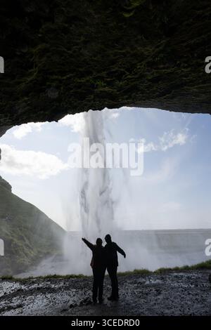 Islande, Sud de l'Islande. Seljalandsfoss, la cascade la plus connue du sud-ouest de l'Islande. Couple sous cascade. Banque D'Images