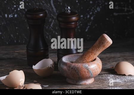 Mortier et pilon en marbre rose et coquilles d'œufs sur fond rustique en bois Banque D'Images