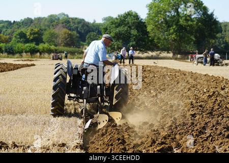 Agriculteur utilisant un tracteur d'époque dans les champs pendant le labourage. Labourage Vintage, Rousham, Angleterre Banque D'Images