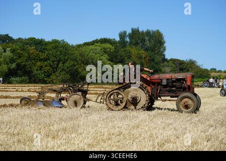 Agriculteur utilisant un tracteur d'époque dans les champs pendant le labourage. Labourage Vintage, Rousham, Angleterre Banque D'Images