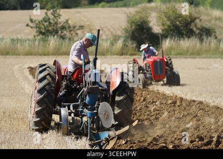 Deux agriculteurs utilisant des tracteurs d'époque dans les champs ruraux pendant l'activité agricole. Labourage Vintage, Rousham, Angleterre Banque D'Images