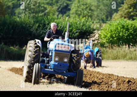 Deux agriculteurs utilisant des tracteurs d'époque dans les champs ruraux pendant l'activité agricole. Labourage Vintage, Rousham, Angleterre Banque D'Images