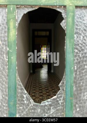 Un couloir en béton symétrique avec un effet de point de fuite, encadré par des motifs géométriques répétés et un éclairage doux. Banque D'Images