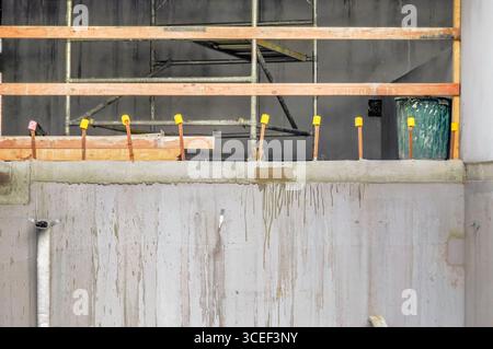 Un chantier de construction avec des murs en béton, des zones clôturées, des matériaux de construction dispersés et des barres d'armature en métal recouvertes Banque D'Images
