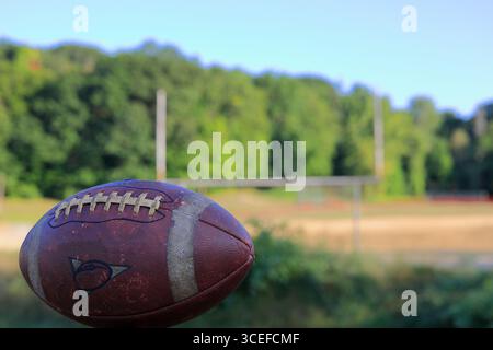 Gros plan d'un vieux ballon de football usé. Goalpost apparaît en arrière-plan. Banque D'Images