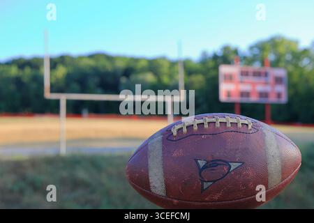 Gros plan d'un vieux ballon de football usé. Scoreboard et Goalpost apparaissent en arrière-plan. Banque D'Images