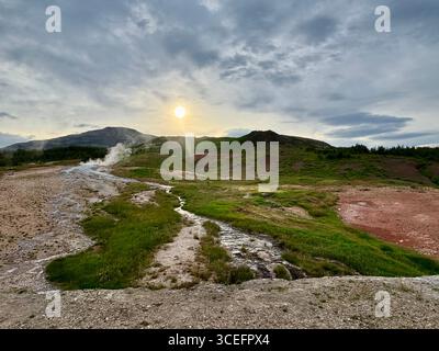 Coucher de soleil en été avec le dôme de lave de Laugarfjall en arrière-plan du champ géothermique de la vallée de Haukadalur. Banque D'Images