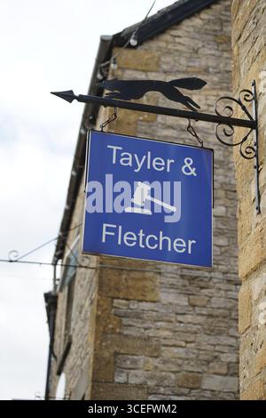 Signe suspendu en métal de Tayler & Fletcher contre mur de pierre à l'extérieur. Stow-on-the-Wold, Angleterre Banque D'Images