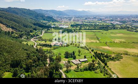 Vue aérienne époustouflante sur le paysage verdoyant du nord de Bogotá, en Colombie, mettant en valeur les collines, les champs et le développement urbain. Banque D'Images