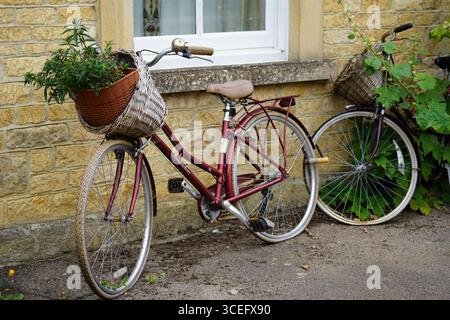 Vélo vintage avec panier en osier appuyé contre le mur de briques à l'extérieur. Chipping Norton, Angleterre Banque D'Images