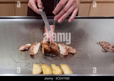 Cuisine teppanyaki avec du bœuf Kobe grillé, de la graisse dorée, des champignons et des légumes disposés sur une plaque métallique grésillante Banque D'Images