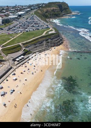 Vue aérienne de Nobbys Beach baignée de soleil où le sable doré rencontre l'océan turquoise sous le regard de Nobbys Headland, Newcastle, Nouvelle-Galles du Sud, Australie. Banque D'Images