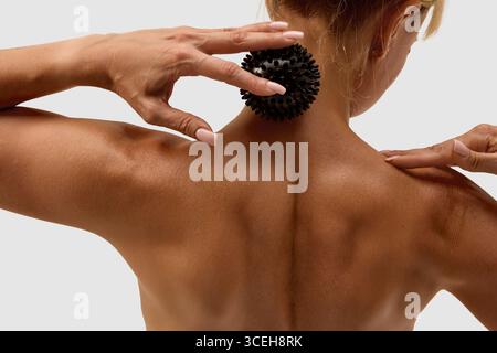 Femme utilisant la boule de massage épi noir sur les muscles du cou et de l'épaule Banque D'Images