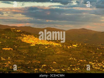 Vue aérienne de l'ancienne ville perchée de colline se prélasser dans la lumière dorée du crépuscule, entourée de collines et de montagnes lointaines, Cortona, Toscane, Italie. Banque D'Images