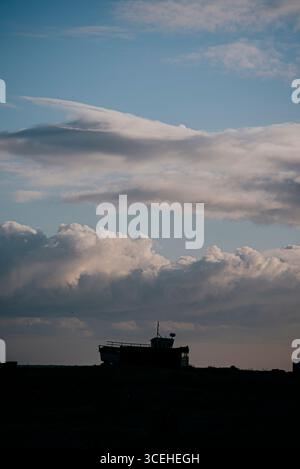 Un bateau est assis sur une colline au milieu d'un ciel nuageux. Le ciel est principalement bleu avec quelques nuages dispersés. Scène est calme et paisible, w Banque D'Images