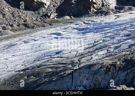 Vue sur le glacier accidenté de Morteratsch, sa surface glacée gravée de profondes crevasses sous un ciel dégagé, le long du terrain rocheux, Pontresina, Grisons, SW Banque D'Images