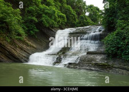 Vue sur la cascade descend gracieusement au-dessus des rochers stratifiés, embrassés par des arbres verdoyants, créant une oasis sereine, Mirsharai, Chittagong Division Banque D'Images