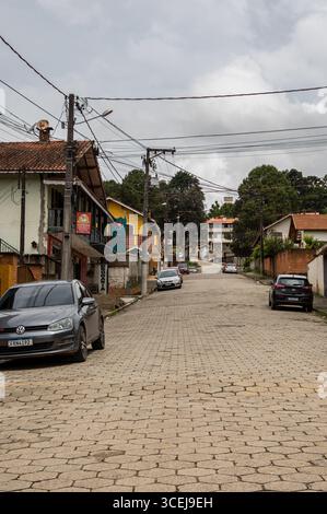 Pedra Partida vue sur la rue avec des maisons traditionnelles, beaucoup de voitures garées et des lignes électriques aériennes sous un ciel nuageux d'été après-midi. Banque D'Images