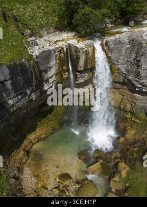 Une grande cascade se déverse dans une piscine de couleur turquoise, entourée de pierres couvertes de mousse, vue aérienne, cascade Okatse, Kinchkha, cascade en trois Banque D'Images