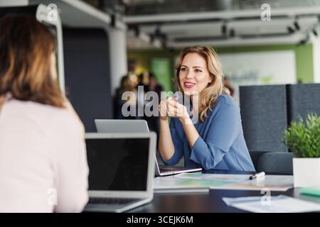 Deux collègues femmes analysant les documents de projet dans un bureau moderne. Banque D'Images