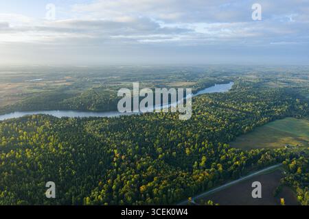 Vue aérienne drone du lac entouré de forêts et de champs en Lituanie, Europe. Paysage naturel pittoresque avec verdure, eau et horizon Banque D'Images