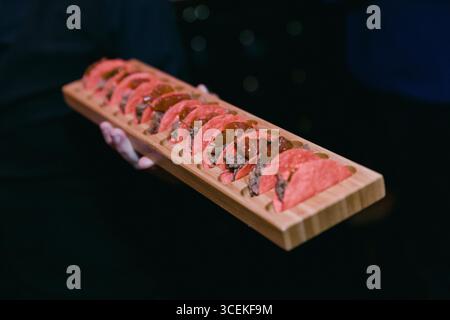 Un plateau de sushis magnifiquement arrangé avec différents styles servis par un chef dans un restaurant confortable pendant le dîner. Banque D'Images