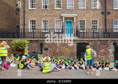 Groupe d'enfants assis sur le trottoir en face de l'ancien bloc de l'hôpital à l'intérieur de la Tour de Londres, Tower Hamlets, London, England, United Kin Banque D'Images