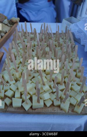 Une planche de bois est remplie de centaines de petits cubes de fromage crétois jaune, chacun broché d'un cure-dent. Délicieux hors-d'œuvre. Banque D'Images