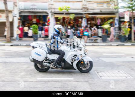Police malaisienne polis motocycliste sur Kawasaki vélo balade le long de la rue avec arrière-plan flou des magasins et des piétons George ville Penang Malaisie Banque D'Images