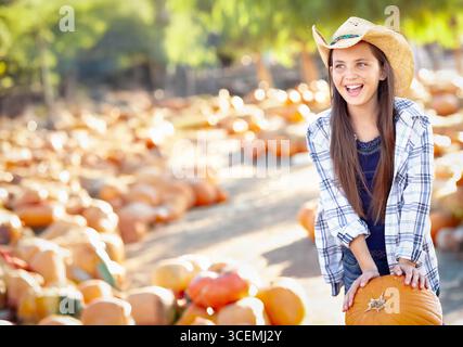 Jolie fille portant un chapeau de cowboy appréciant le Patch de citrouille sur un jour d'automne ensoleillé. Banque D'Images