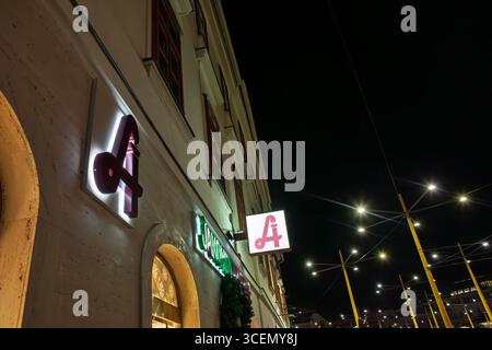 GRAZ, AUTRICHE - 17 DÉCEMBRE 2024 : enseigne de pharmacie autrichienne avec le symbole rouge D'Un serpent à Graz la nuit. Le logo représente l'accès public aux soins de santé Banque D'Images