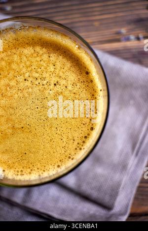 Gros plan du café fraîchement infusé avec de la mousse crémeuse, stylisé sur une table en bois rustique avec des accents de lavande, parfait pour les arrière-plans, l'image de marque de café, et Banque D'Images