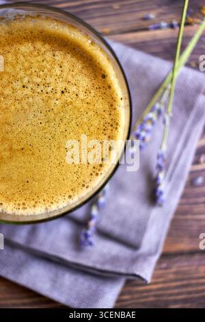Gros plan du café fraîchement infusé avec de la mousse crémeuse, stylisé sur une table en bois rustique avec des accents de lavande, parfait pour les arrière-plans, l'image de marque de café, et Banque D'Images