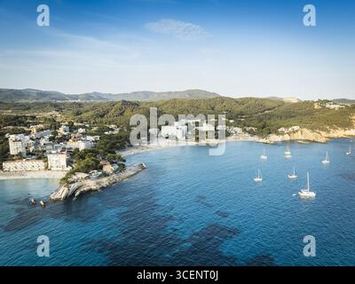 Vue aérienne des eaux turquoise rencontrer les plages de sable près de 62A Bulevar de Peguera, encadrée par une végétation luxuriante et des montagnes lointaines, Peguera, Illes Balear, Espagne. Banque D'Images