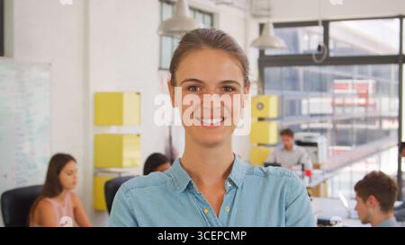 Tête et épaules Portrait de sourire jeune femme d'affaires dans le bureau occupé Banque D'Images