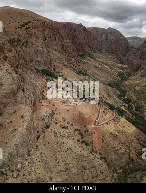 Vue aérienne du monastère de Noravank niché au milieu des falaises accidentées et ensoleillées, témoignage de l'histoire sur fond de canyon spectaculaire, Noravank Monastery Road, province de Vayots Dzor, Arménie. Banque D'Images