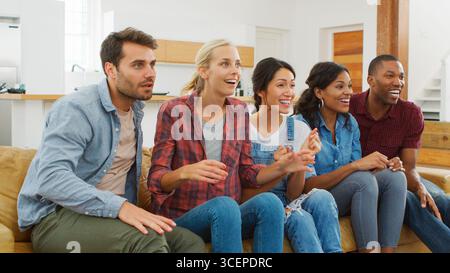 Groupe de jeunes amis regarder du sport à la télévision et acclamer Banque D'Images