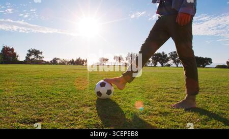 Gros plan d'un homme jouant au football dans un parc avec Lens Flare Banque D'Images