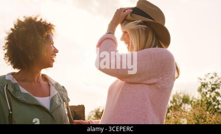 Portrait en plein air de deux amies féminines matures souriantes contre un soleil éclatant Banque D'Images