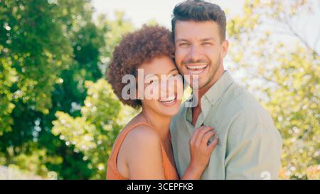 Portrait d'amour Multi-racial couple debout à l'extérieur dans le parc de jardin ou la campagne Banque D'Images