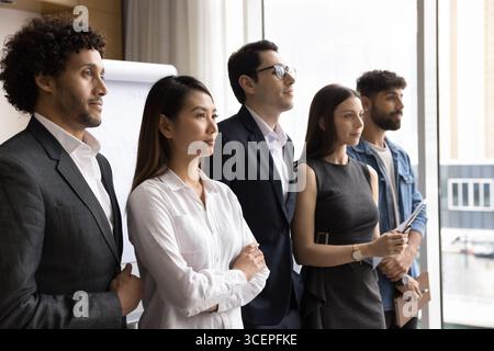 Ambitieuse équipe d'affaires multiethnique millénaire se tient dans la rangée regarder vers l'avenir Banque D'Images