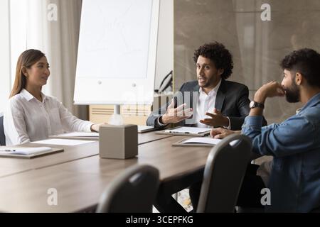 Un jeune homme d'affaires confiant exprime son opinion à divers collègues de travail dans la salle de réunion Banque D'Images