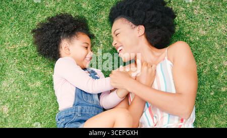 Photo au-dessus du ciel de mère et fille souriantes allongées sur herbe dans le jardin ensemble Banque D'Images