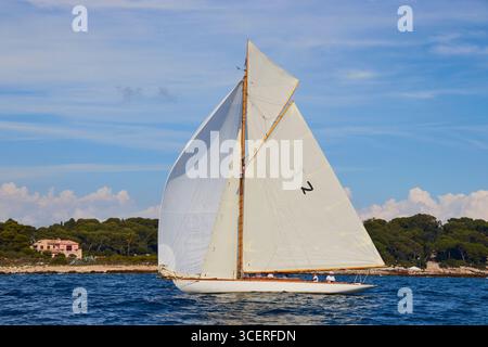 Yacht à voile classique en eaux ouvertes avec vue panoramique de fond côtière Banque D'Images